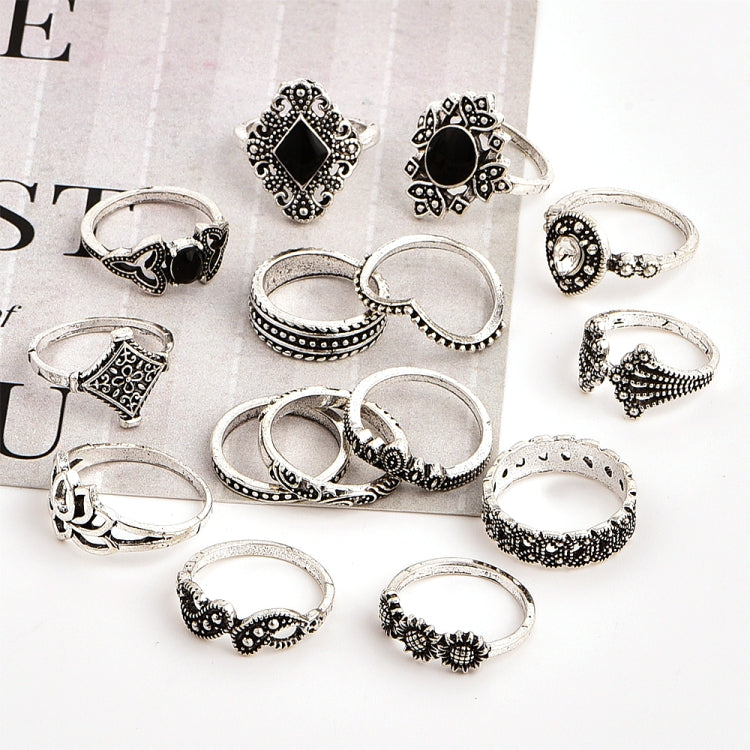 Assorted silver-tone rings with black stones and filigree details, scattered on a surface