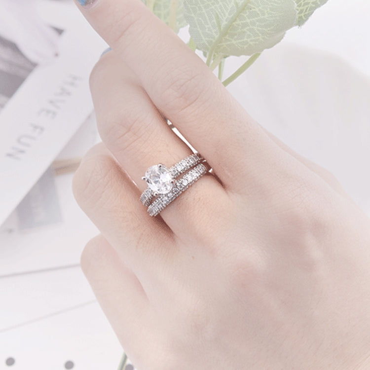 Cubic zirconia engagement ring with round center stone on finger, silver-tone double band