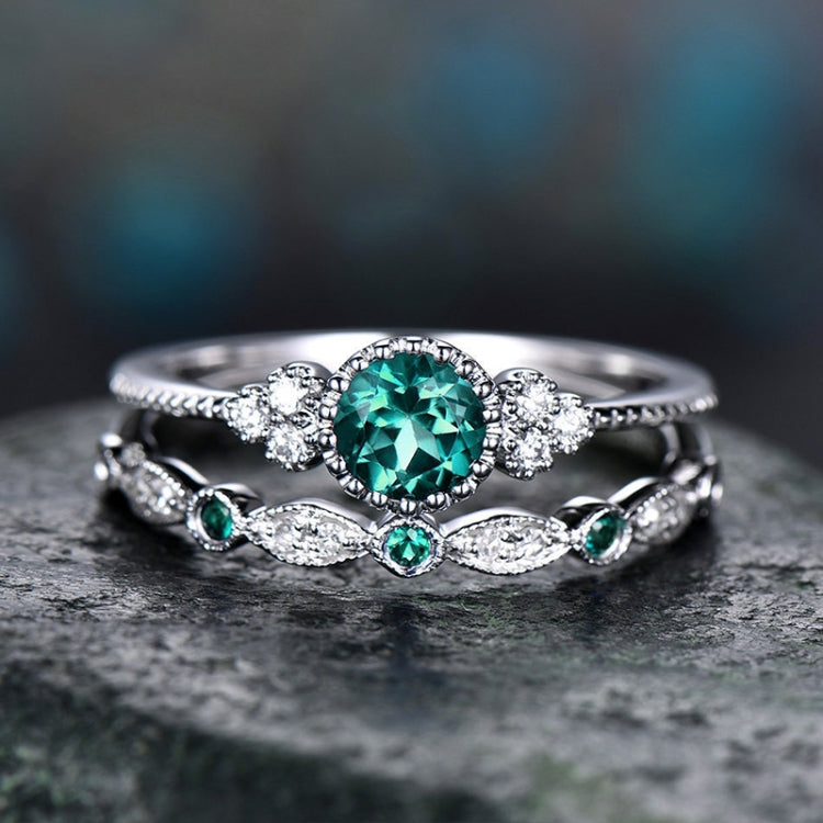 Silver-tone rings set with round teal center stone, halo stones, and green side accents