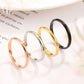 Set of four glossy metal rings: black, gold, rose gold, and silver