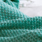 Knitted mermaid tail blanket in teal, close-up of textured fabric weave