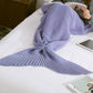 Knitted mermaid tail blanket in light purple, fin tail spread on bed