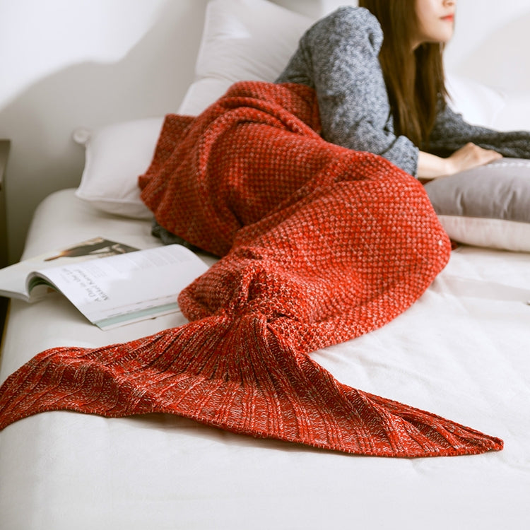 Knitted mermaid tail blanket in rust orange, fin tail stretched on bed