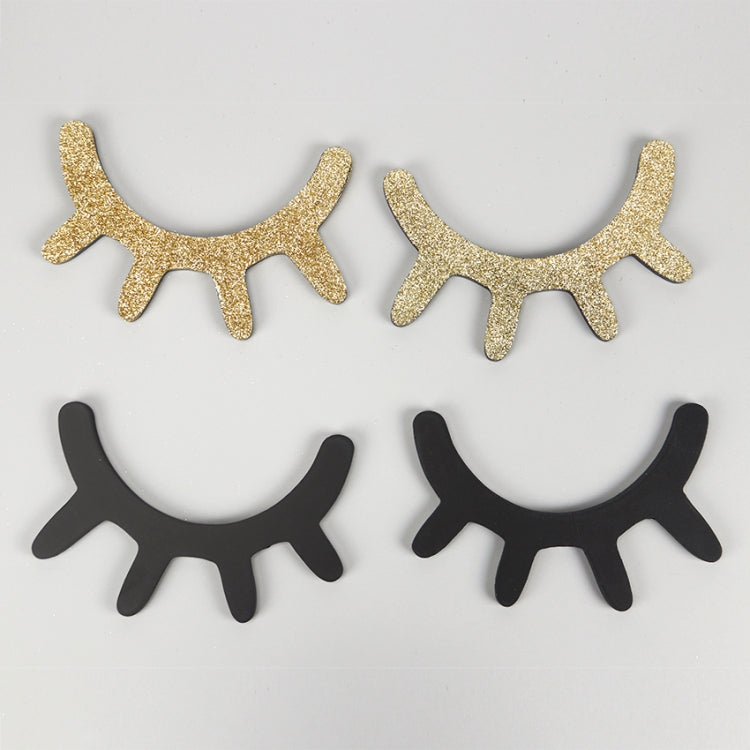 Pair of 3D eyelash wall stickers in gold and black, curved lash shapes