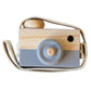Children's wooden camera toy with light blue body, round lens, and fabric strap