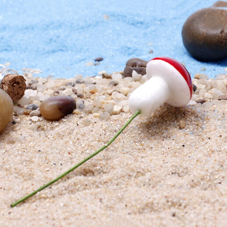 Mini white-and-red foam mushrooms on sandy ground, with small green stems