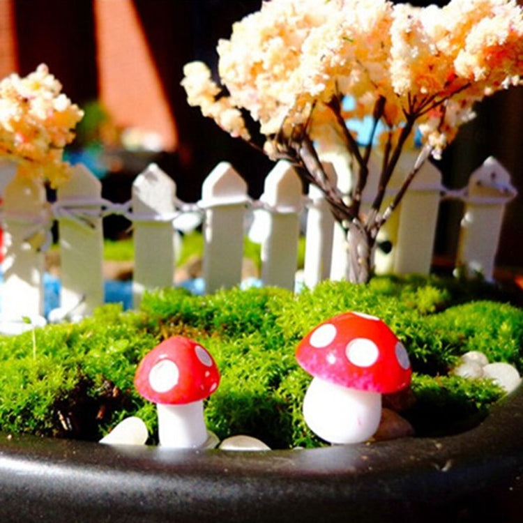 Mini foam mushrooms with red caps, white spots, and white stems beside miniature fence