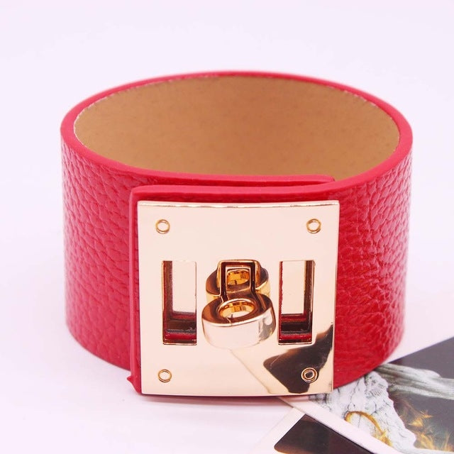 Wide red leather cuff bracelet with gold-tone square logo plate and riveted metal clasp