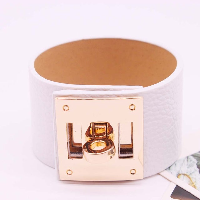 Wide white leather cuff bracelet with gold-tone square logo plate and riveted metal clasp