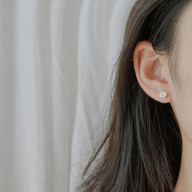 Round zircon stud earring on ear, small clear stone with push-back post