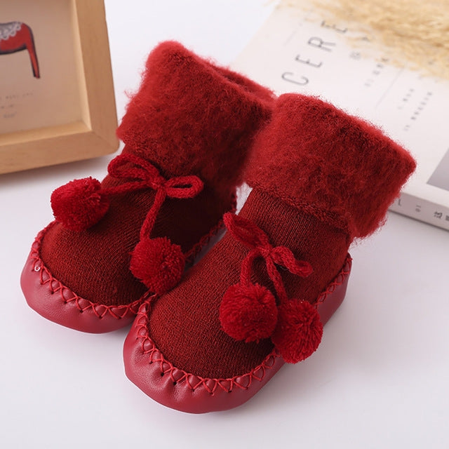 Red plush baby floor socks with pom-pom accents and tie bows