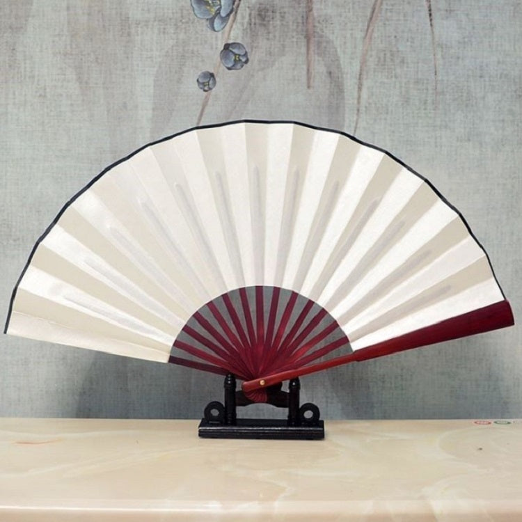 White blank silk folding fan with dark red inner circle and maroon radial border on a stand.