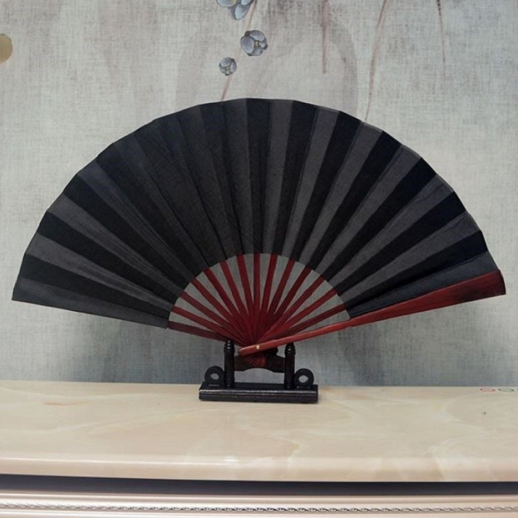 Black blank silk folding fan with dark red inner circle and maroon radial stripes on a stand.