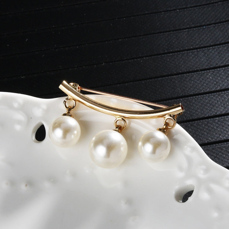 Gold-tone pearl bar brooch with three round white pearls on a curved pin bar