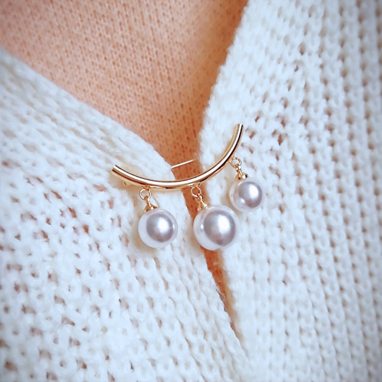 Gold-tone pearl bar brooch on white knit fabric with three dangling white pearls
