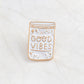 Enamel bottle brooch pin with gold outline and “Good Vibes” text, star details.