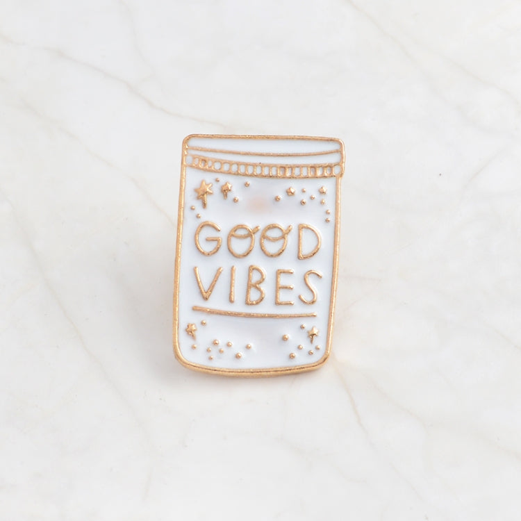 Enamel bottle brooch pin with gold outline and “Good Vibes” text, star details.