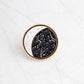 Round enamel moon constellation pin with gold border, dark blue sky and stars.