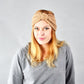 Beige knitted turban headband with wide knot bow, textured crochet knit, stretch hair wrap