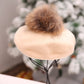 Beige fuzzy beret-style beanie with brown pom-pom and drawstring ties