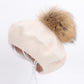 Beige plush beanie with tan pom-pom and visible elastic drawstring