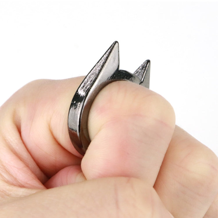 Silver finger defense ring worn on a hand, featuring three-point spikes
