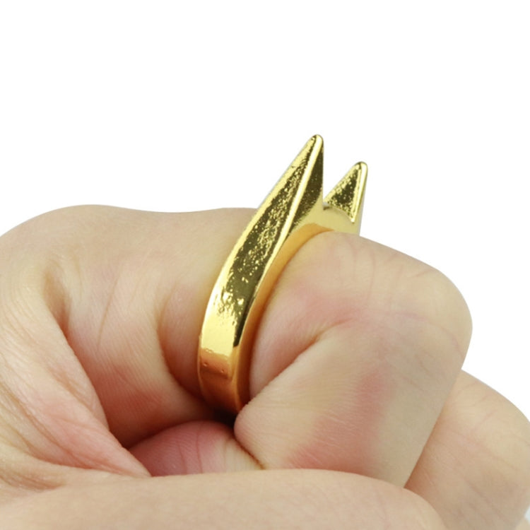 Gold-tone finger defense ring worn on a hand with sharp raised spikes