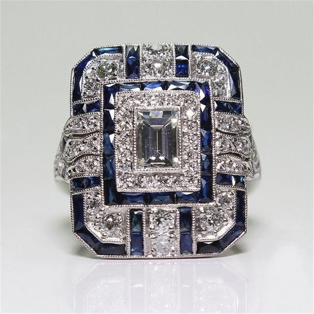 Princess-cut style engagement ring featuring a square center and blue gem accents