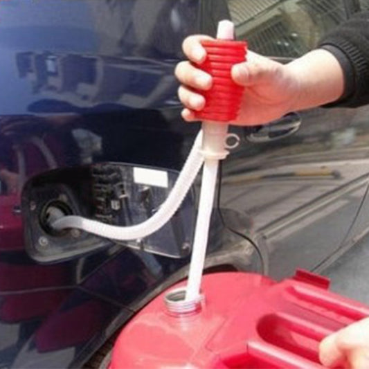 Red manual siphon pump with white transfer hose, hand holding pump for liquid transfer
