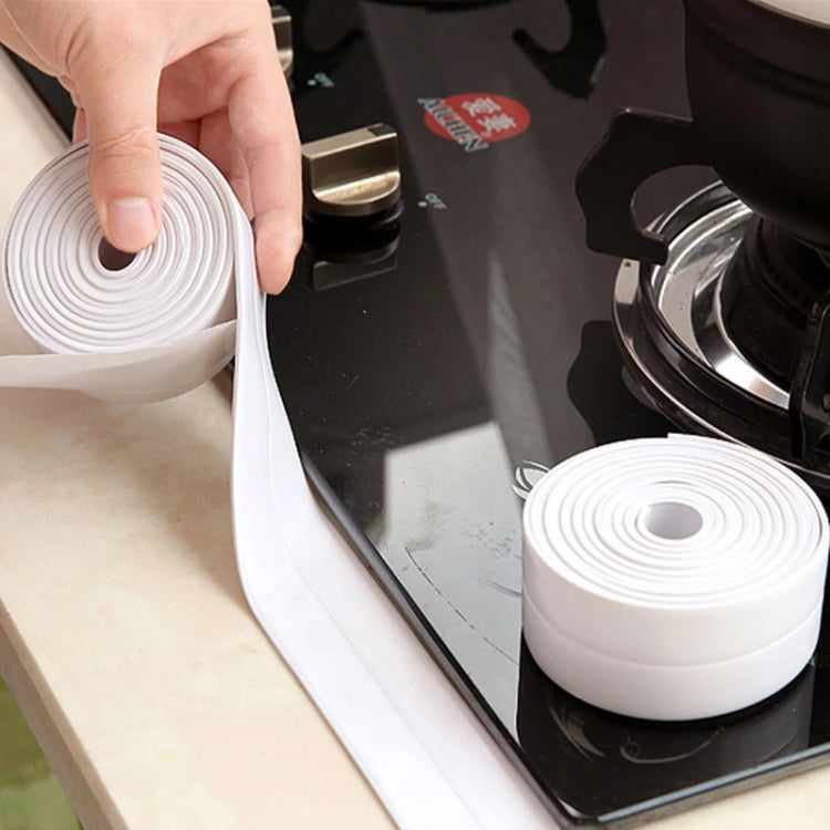 White waterproof adhesive sealing tape roll held near a stovetop backsplash