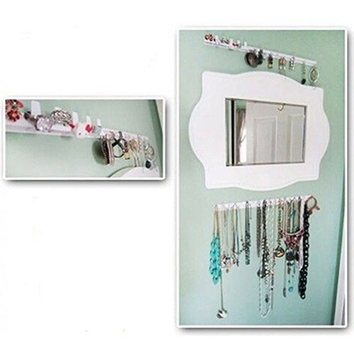Adhesive jewelry hook rails mounted on a wall beside a mirror, holding necklaces