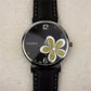 Ladies quartz watch with black leather strap, silver case, black dial with gold glitter four-leaf clover