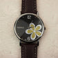 Ladies quartz watch with brown leather strap, silver case, black dial with gold glitter four-leaf clover