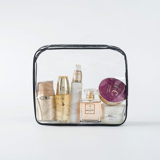 Clear PVC cosmetics bag with black trim, filled with skincare bottles and jar