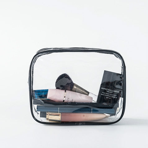 Clear PVC zipper pouch with black trim, holding makeup and beauty items
