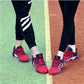 Red trekking sneakers on feet with lace-up design and grippy outdoor sole