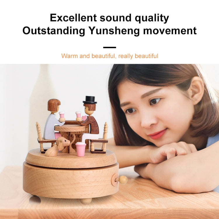 Wooden rotating music box on tabletop with couple figures and pink cups, round base