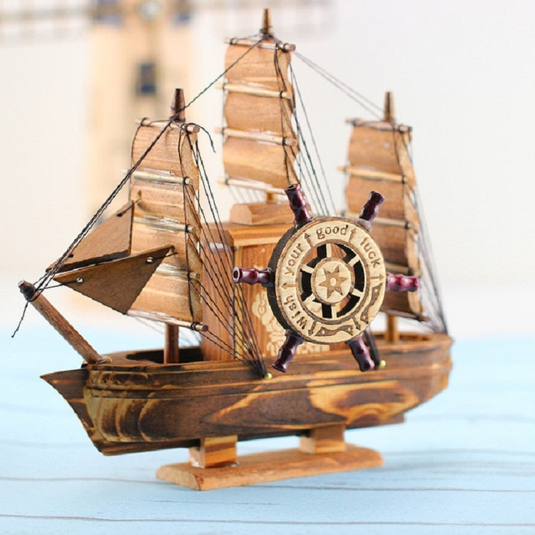 Wooden sailboat ornament with detailed sails, rigging, and compass-style ship wheel