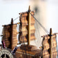 Wooden sailboat decoration with stacked decks, sails, and taut rope rigging lines