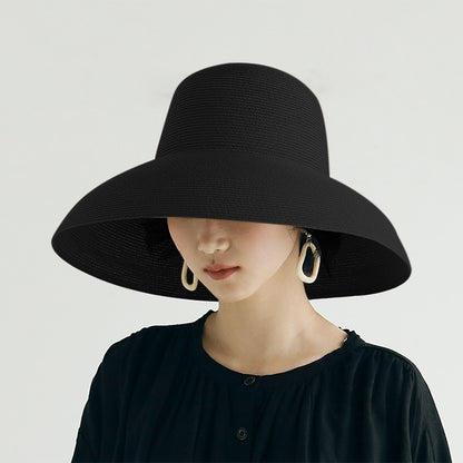 Black straw sun hat with wide brim and curved crown, on a model