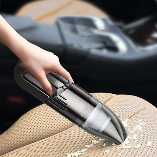 Handheld car vacuum cleaner removing dust from tan car seat upholstery