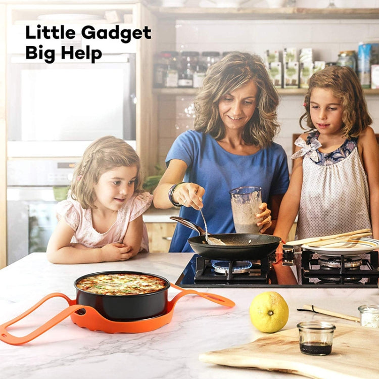 Orange silicone egg steamer basket on kitchen counter beside a skillet