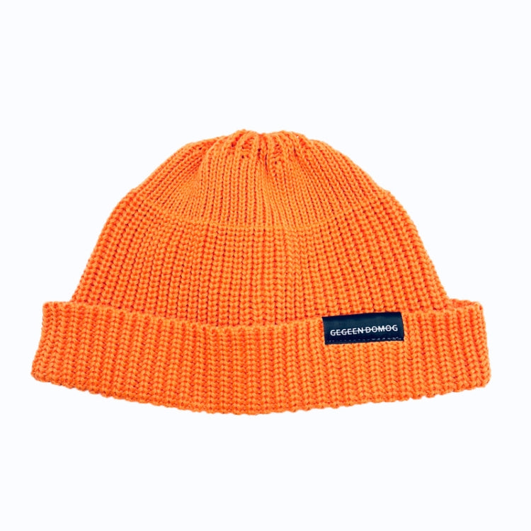 Orange knitted beanie hat with ribbed brim and pom top, one-size, branded label.