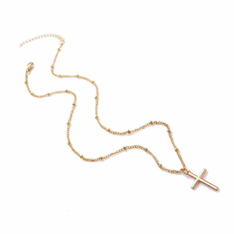 Gold cross pendant necklace lying flat, featuring a small cross charm on a linked chain.