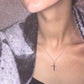 Silver cross pendant necklace on a woman’s neckline with a slim linked chain and cross charm.