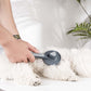 Self-cleaning pet hair brush comb with needle bristles, ergonomic handle on a white dog