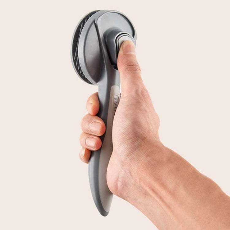 Pet grooming brush held in hand, gray handle with round pin head