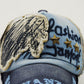 Close-up casual baseball cap in light blue and navy with embroidered face and star details.