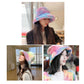 Plush rainbow fisherman bucket hat, pastel rainbow colors on a model.
