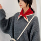 Red and cream knitted wool triangle scarf with white stripes, worn on neck